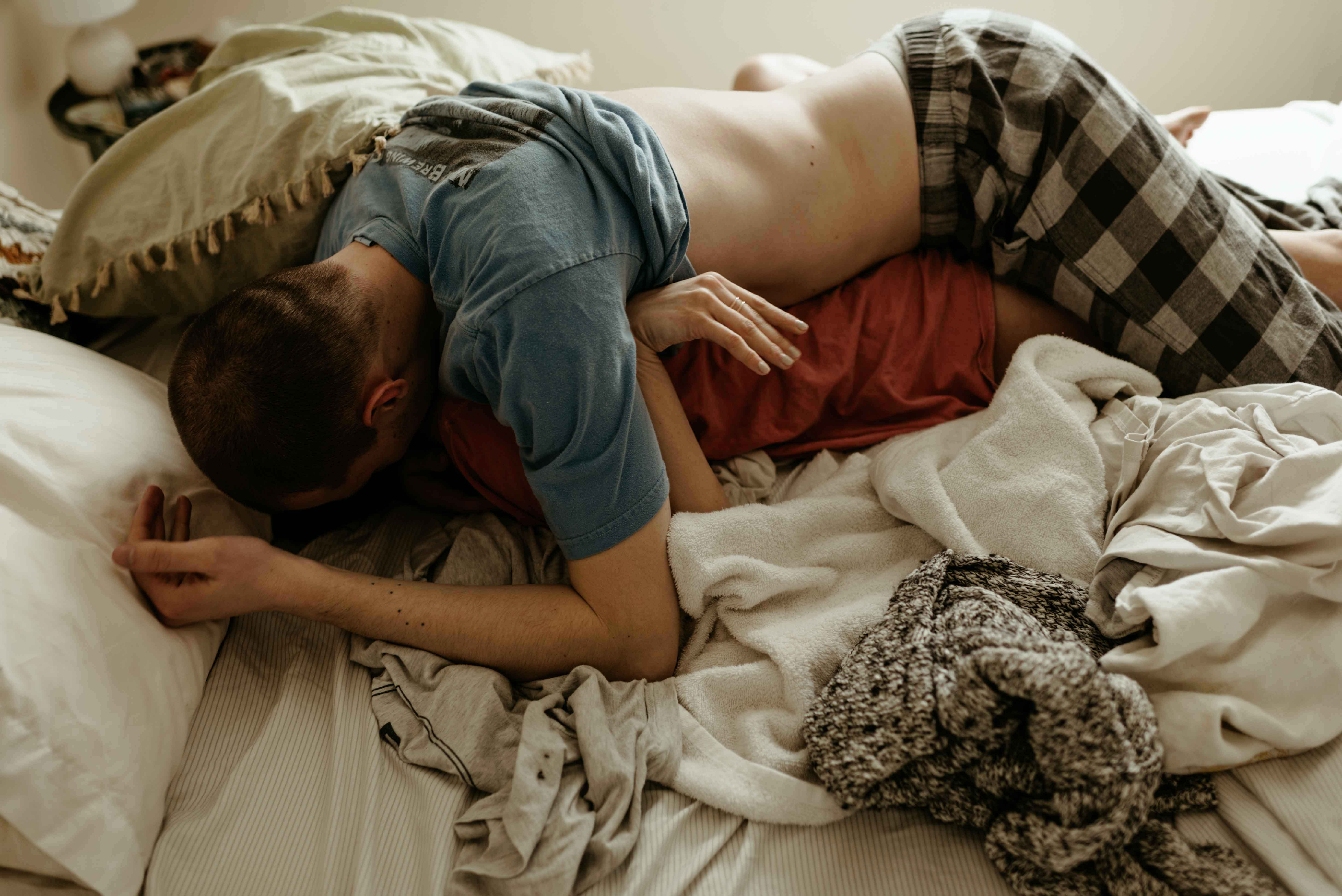 Katie and tj rolling on bed during in-home couples session